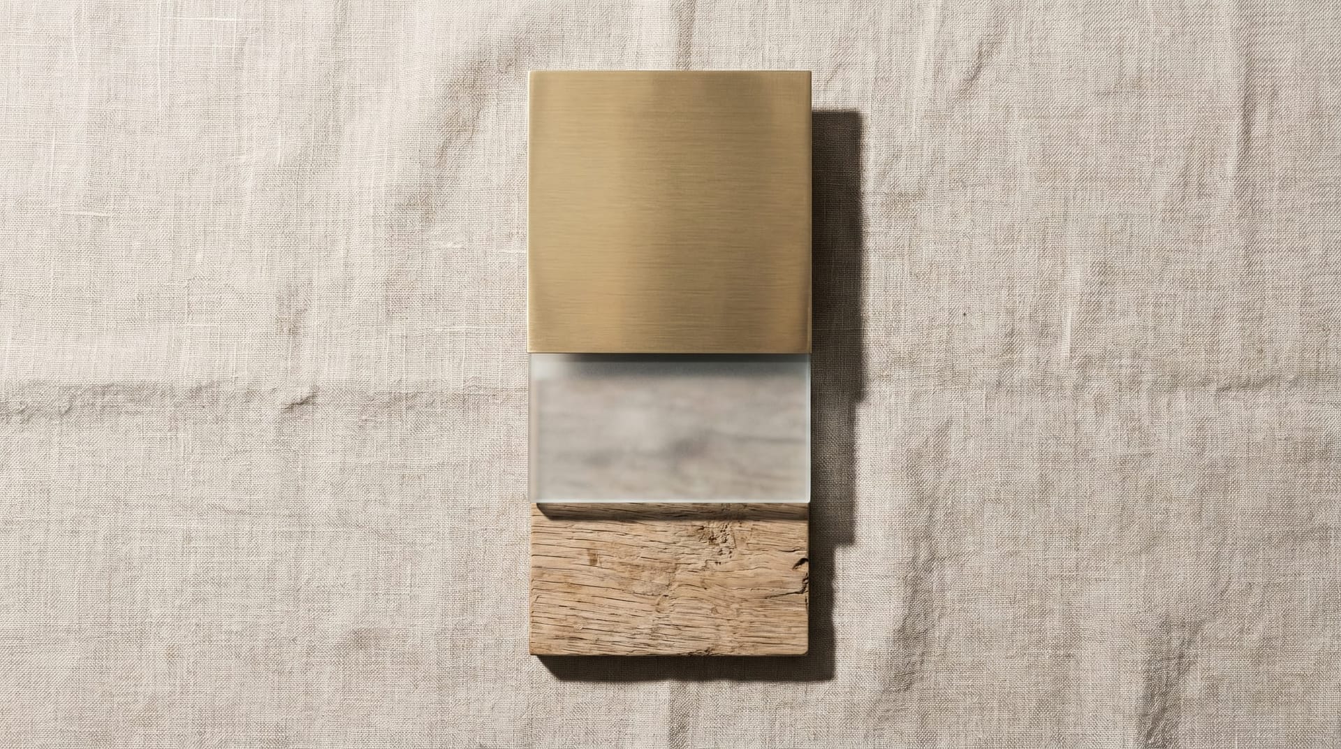 Three precisely stacked panels of brushed brass, frosted glass, and weathered oak resting on linen, representing the three surviving layers of the agentic AI stack after scaffolding-layer absorption.