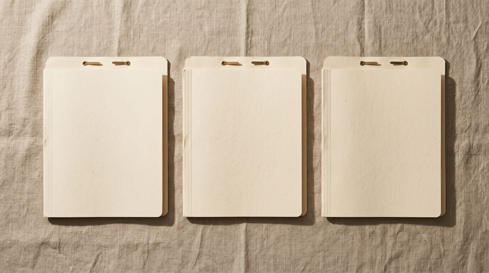 Three identical cream paper folders on a clean linen surface, representing the three single-page outputs of the Cloud Radix Northeast Indiana AI planning pilot.