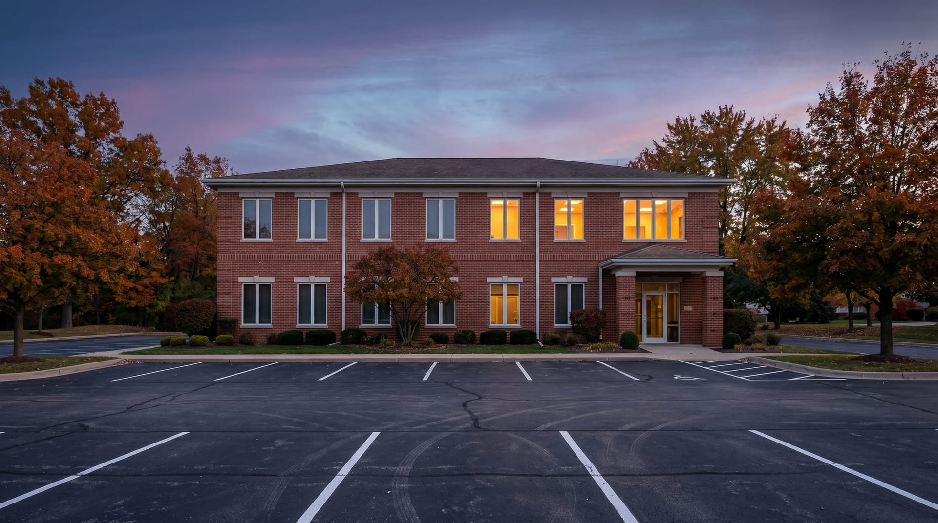 Dusk exterior of a quiet Northeast Indiana medical office building with warm window light and empty parking lot, evoking the scale at which Fort Wayne practices vet AI tools.
